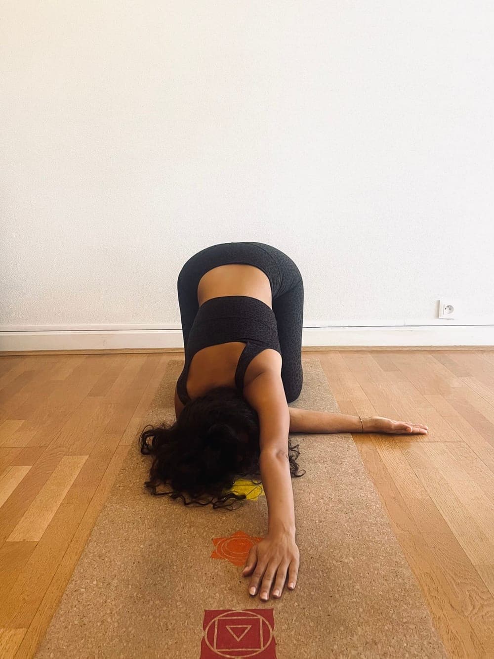 Anaïs en Parsva Balasana, à genoux, un bras glissé sous l'autre, la tête au sol